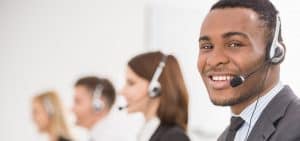 A smiling customer service representative man and his colleague's team working at their desk