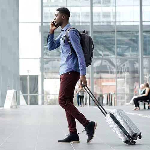 A young man travelling with bag and talking on phone